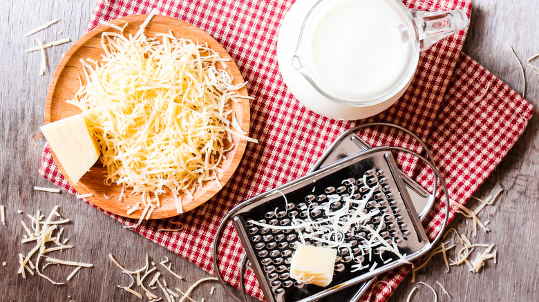 Grated cheese, milk, and cheese grater on tabletop
