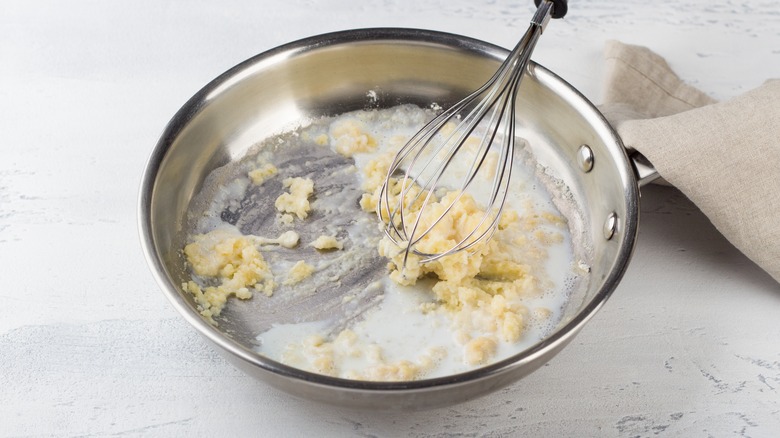 Milk added to a roux in saucepan