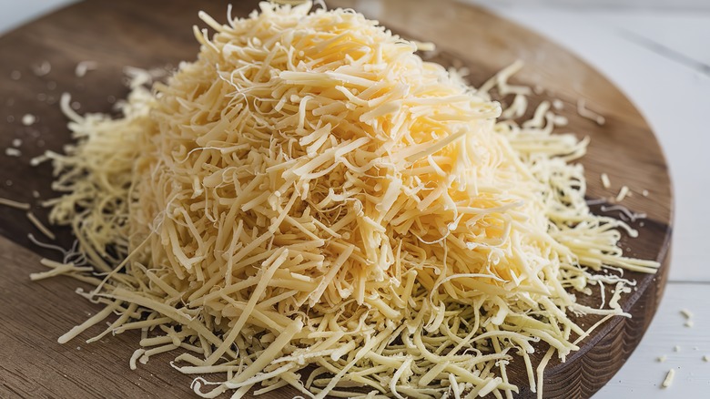 Pile of grated cheese on wood board
