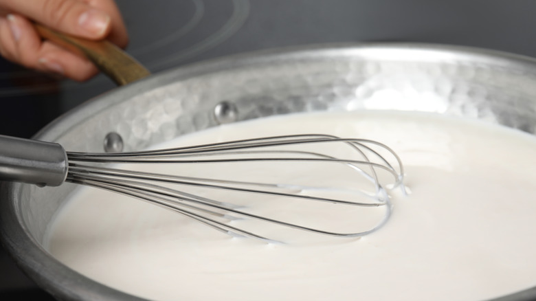Whisk inserted into a saucepan of milk
