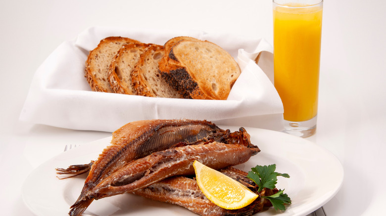 Plate of kippers with lemon, sliced toast, and orange juice