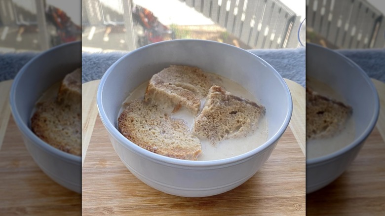 Chunks of toast in a bowl of milk on wooden counter