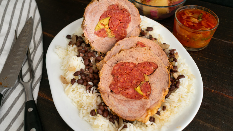 Boliche over black beans and rice on a white plate served wit salsa