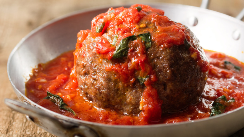 Close up of large meatball in tomato sauce