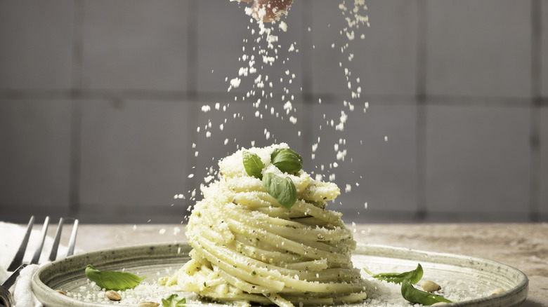 Pasta being garnished with Parmesan cheese