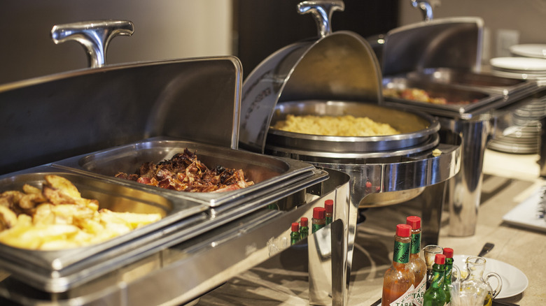 Several dishes in warming trays at a buffet