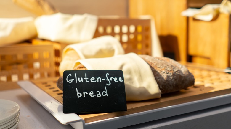 A loaf of bread wrapped in a cloth napkin with a sign saying Gluten-free bread