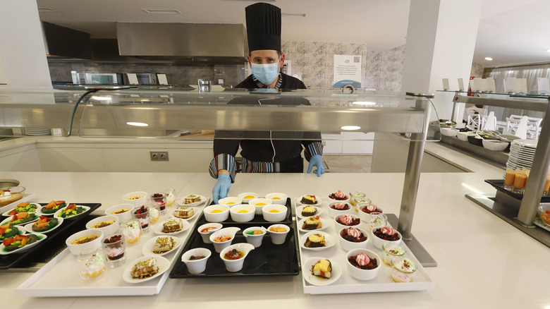 A server behind a buffet with a mask on