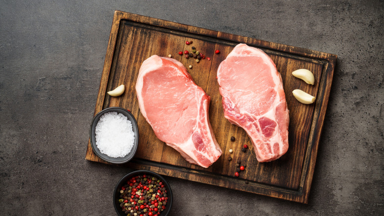 Raw pork steaks on cutting board