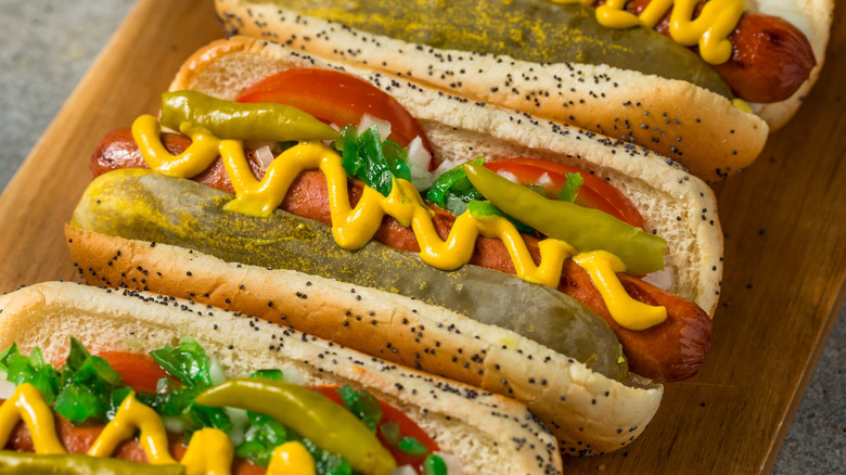 Hot dogs with assorted toppings such as mustard, pickles, and tomatoes