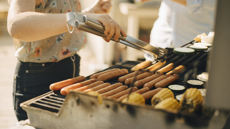 Person grilling hot dogs on grill
