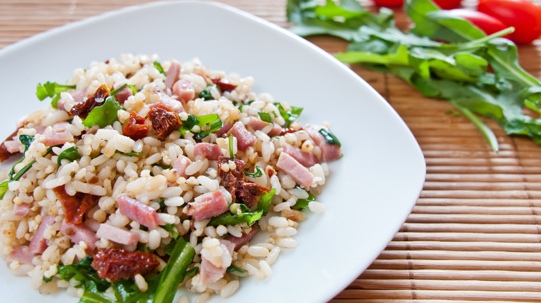 Plate of rice salad with ham and sun dried tomato on bamboo place mat