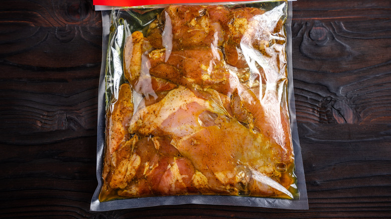 Bag of marinated chicken on wooden counter