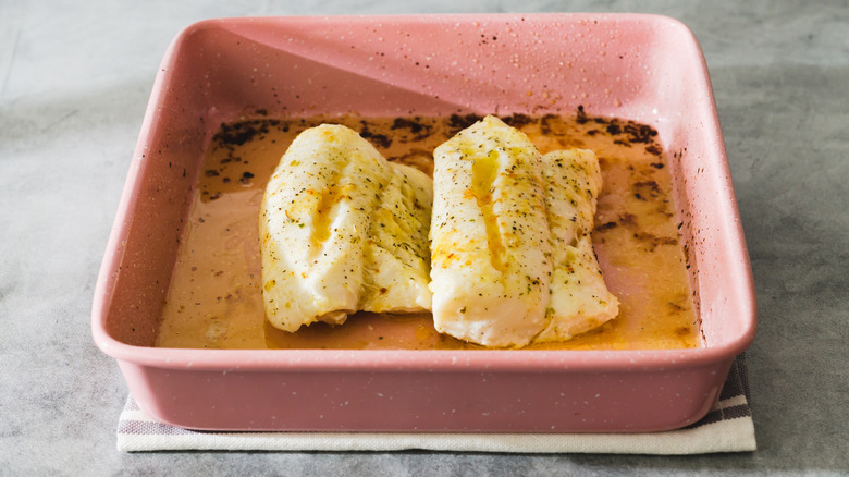 White fish in baking dish with butter or oil