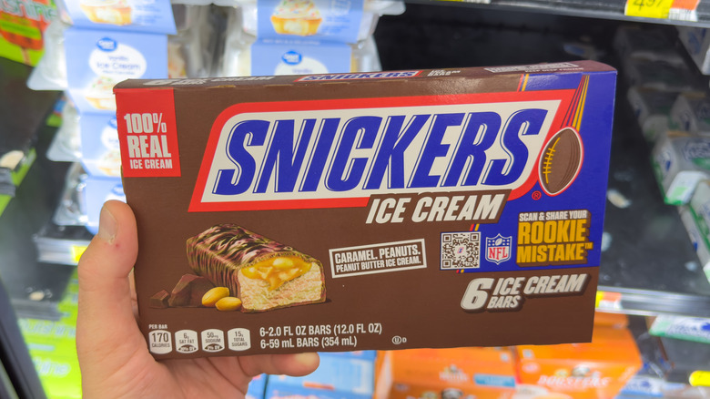 Hand holding a box of Snickers Ice Cream Bars in a store