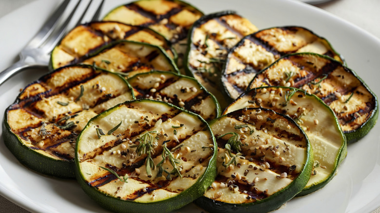 Grilled zucchini slices on a white plate.