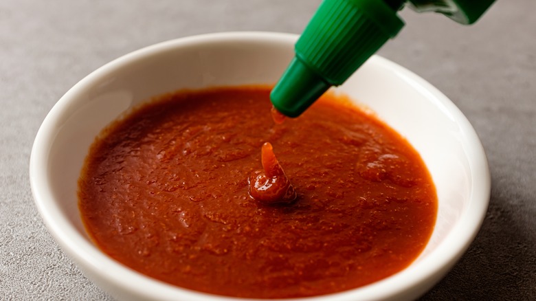 sriracha being squeezed into a bowl