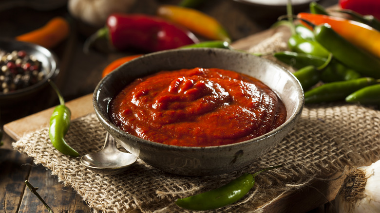 sriracha in a rustic bowl with fresh chiles on the side
