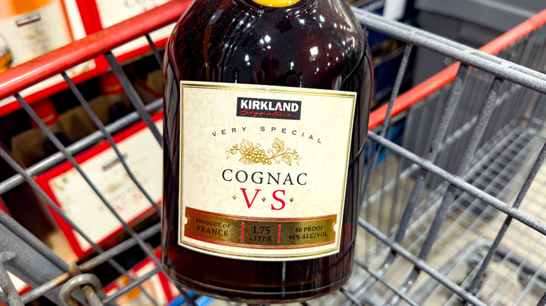 Someone holds a bottle of cognac in a Costco