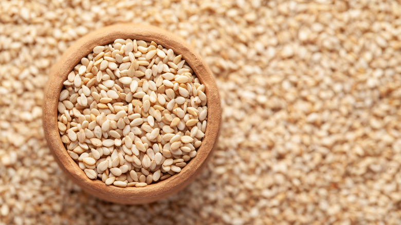 sesame seeds in bowl surrounded by more sesame seeds