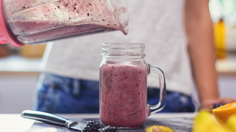 women pouring smoothie from blender into glass