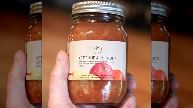 Hand holding a can of ketchup aux fruits