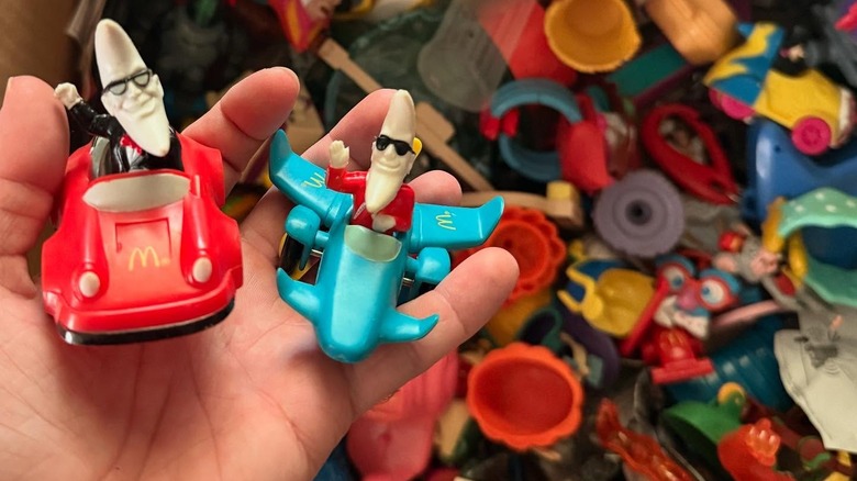 Hand holding two Mac Tonight Happy Meal toys