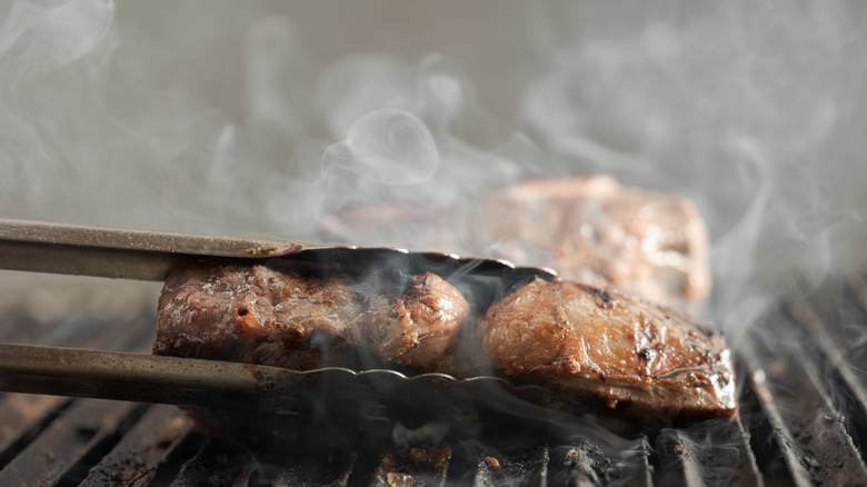 steak cooking on smoky grill