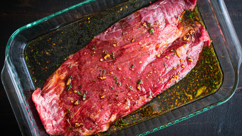 Flank steak marinating in glass baking dish