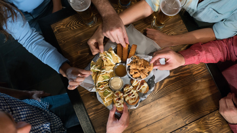 hands reaching for bar food 