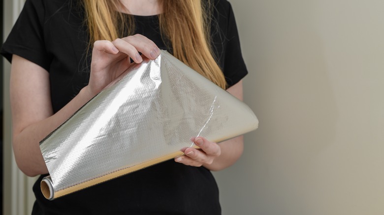 Person unwrapping aluminum foil