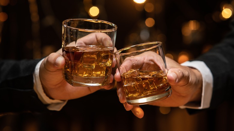 hands toasting whiskey glasses
