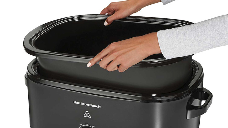 hands removing oven roaster insert