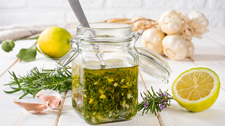 a glass jar of vinaigrette with herbs