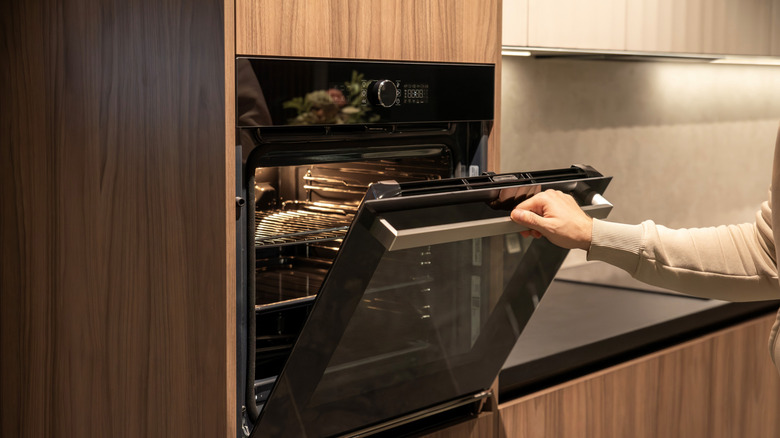 A man opens a built-in electric oven