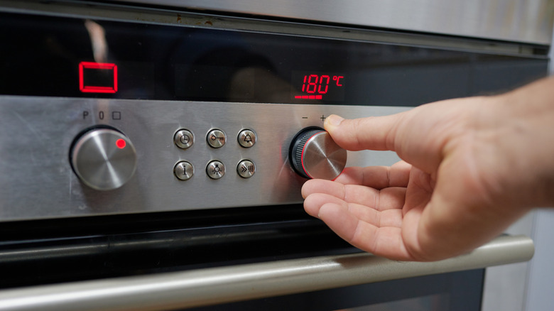 Person using the temperature knob of an oven