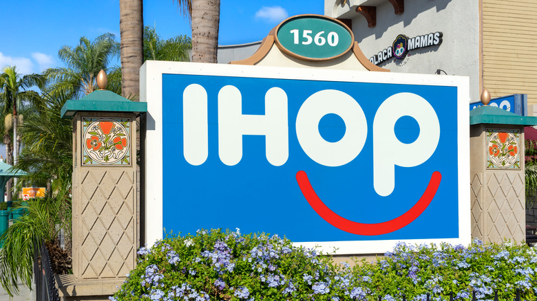 IHOP sign with smiley face logo amidst foliage