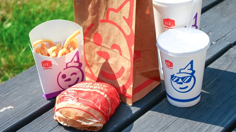 Jack in the Box drinks, fries, and burger arranged on a park bench