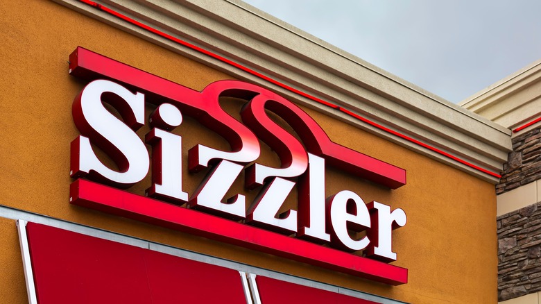 Red and white Sizzler sign on an ochre-colored wall