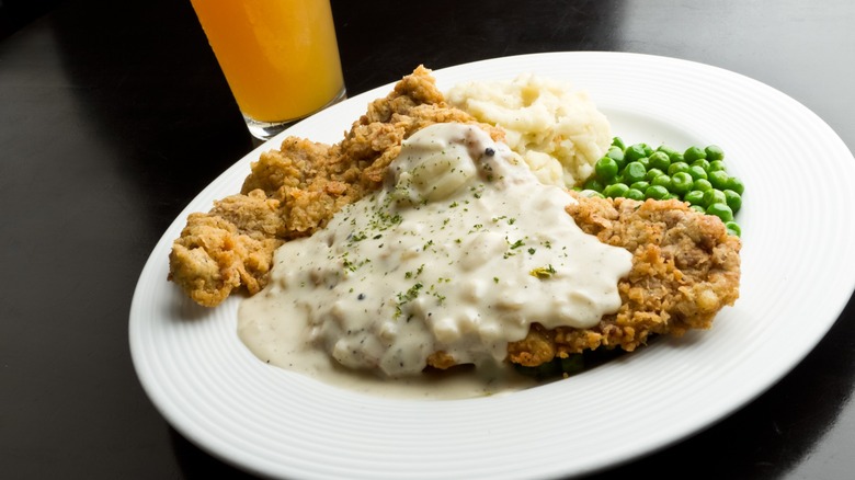 Chicken fried steak with gravy, mashed potatoes, and peas