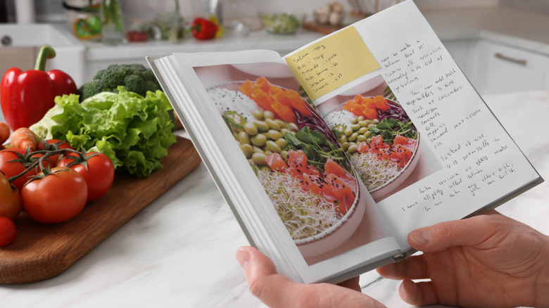Someone reading a cookbook at a marble counter