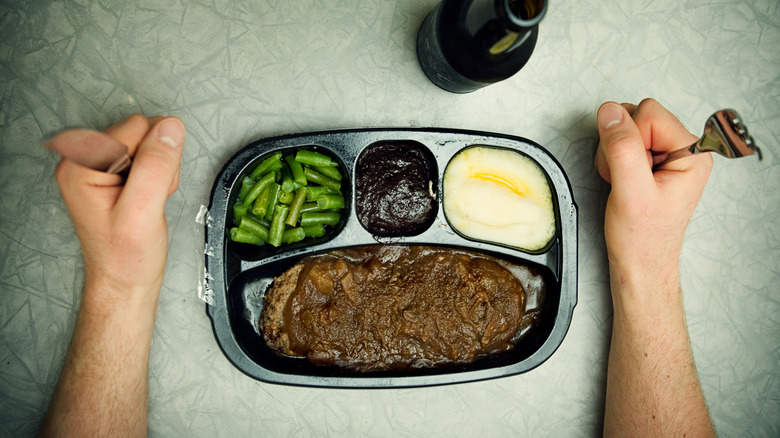 TV dinner prepared with hands ready to dig in