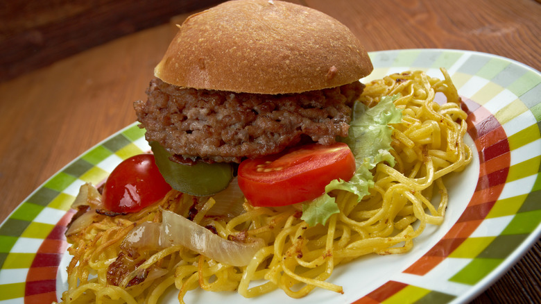A chow mein sandwich on a multicolored plate.