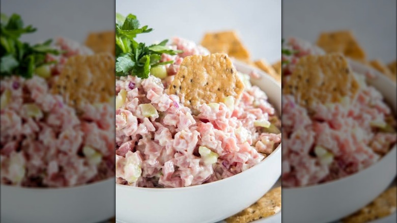 Ham salad in a bowl with crackers and parsley.