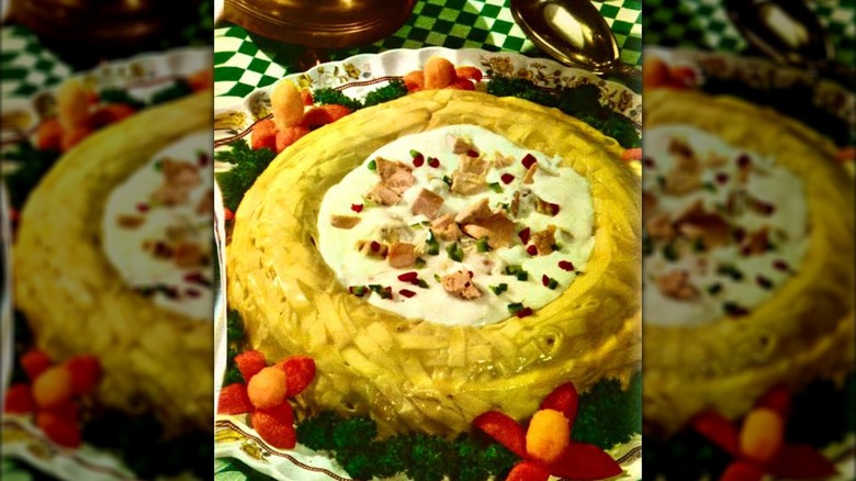 Noodle ring with creamed chicken on a green and white tablecloth.