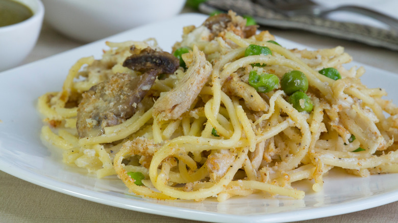 A plate of chicken tetrazzini with peas and parmesan cheese.