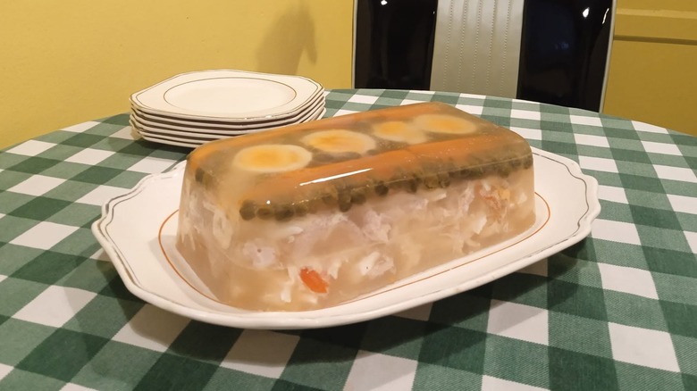 A dish of tube steak and eggs suspended in aspic on a checked tablecloth.