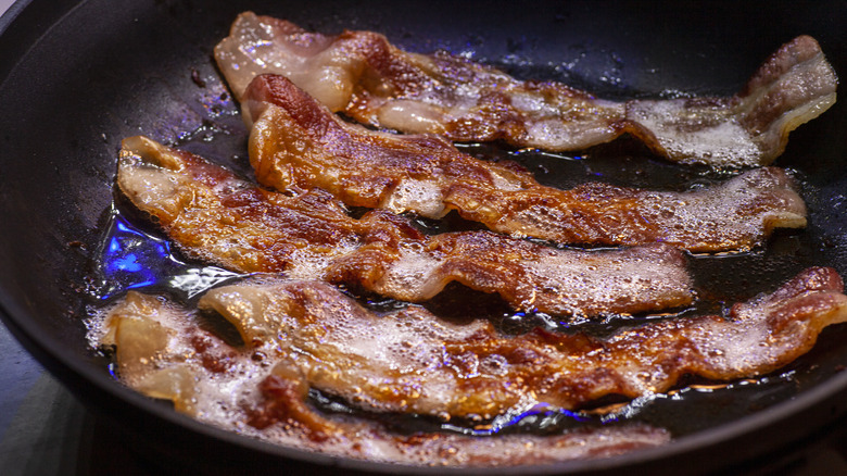 Bacon strips frying in a pan