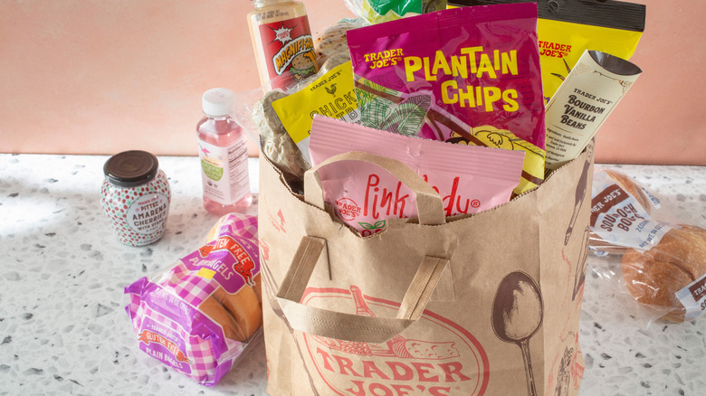 trader joe's bag full of snacks and groceries on a countertop with more products surrounding it