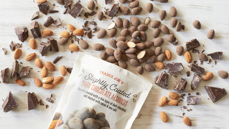 package of Trader Joe's chocolate covered almonds surrounded by many almonds and pieces of chocolate